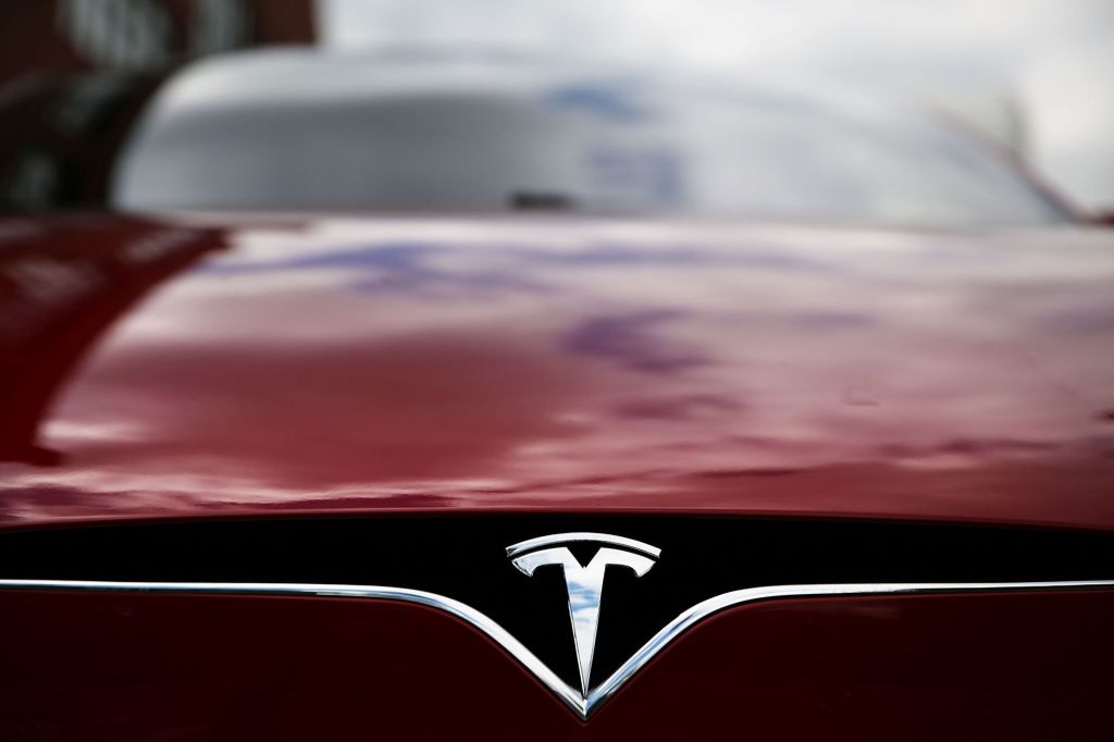 Tesla logo, creator of autopilot, on a red car.