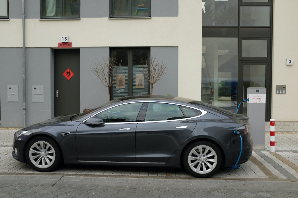  A Tesla Model S electric car charges at a public charging colum
