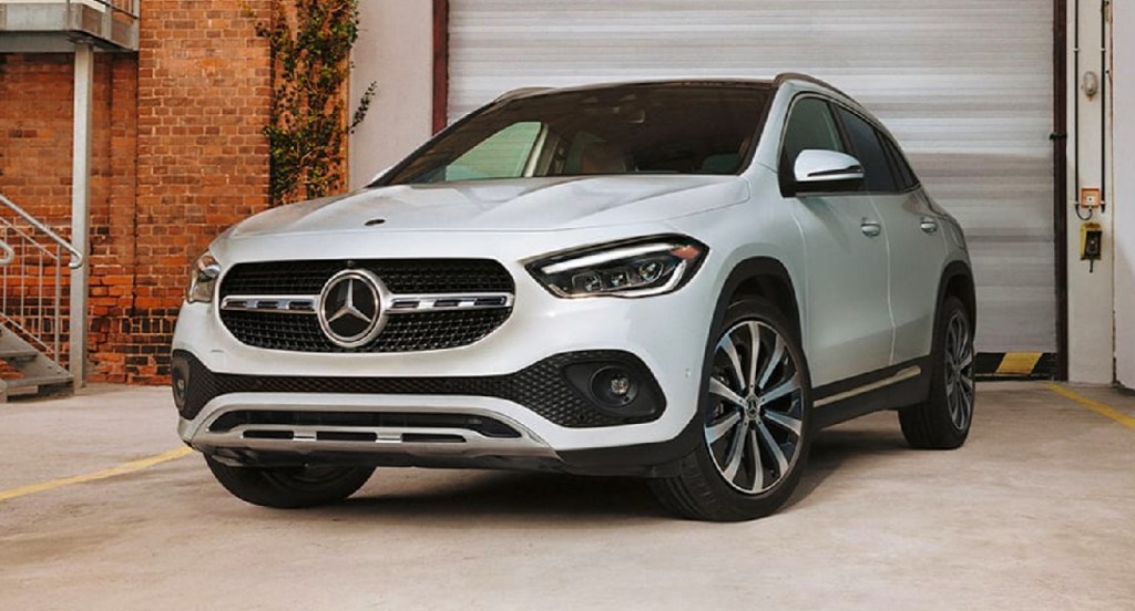 A white Mercedes-Benz GLA luxury SUV is parked outside the garage of a building. 