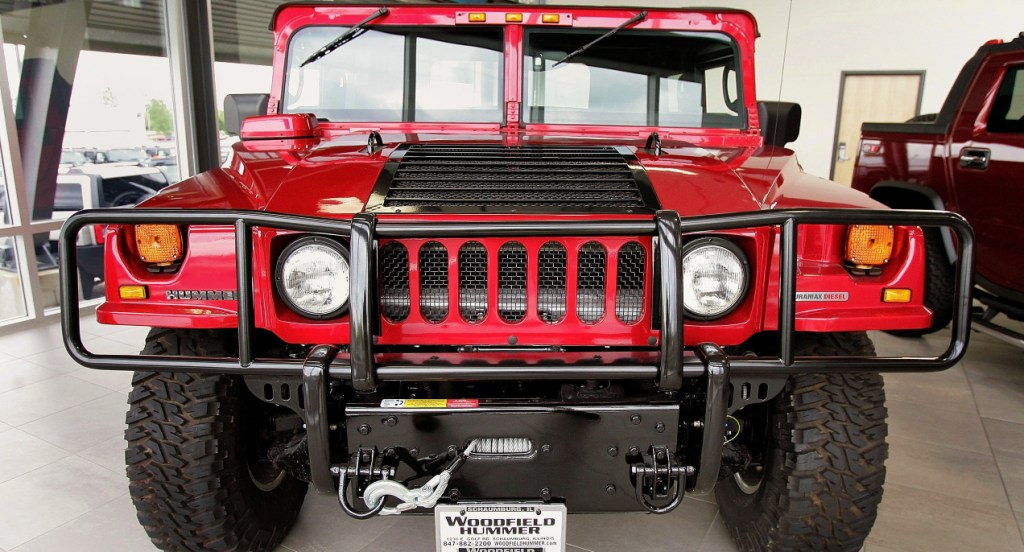 A red Hummer H1 SUV is parked in a showroom. 