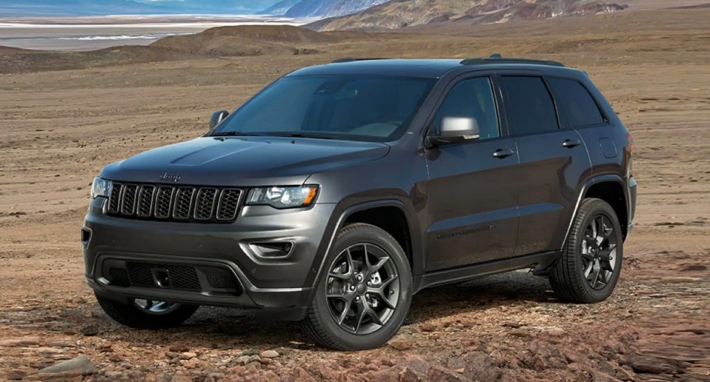 A black Jeep Grand Cherokee SUV is parked off-road. 