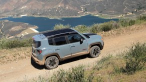 A green Jeep Renegade Trailhawk small off-road SUV is off-roading on a trail.