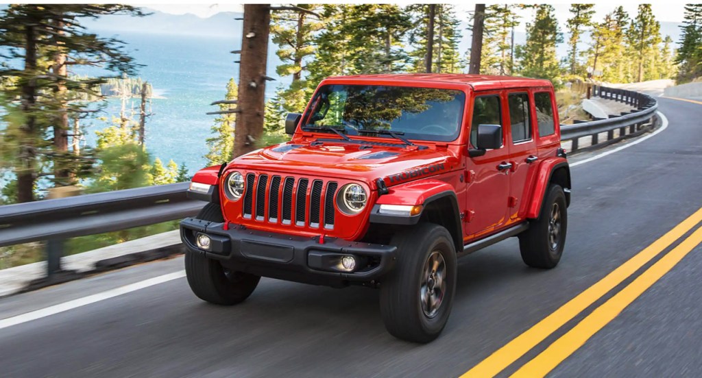 A red Jeep Wrangler is driving on the highway. 