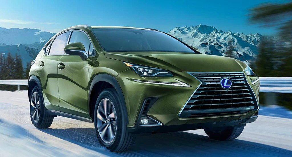 A green Lexus NX 450h+ is driving on a snowy highway. 