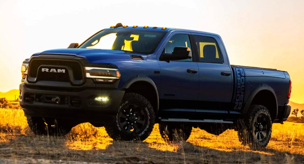 A blue Ram 2500 Power Wagon off-road truck is parked in front of a sunset. 
