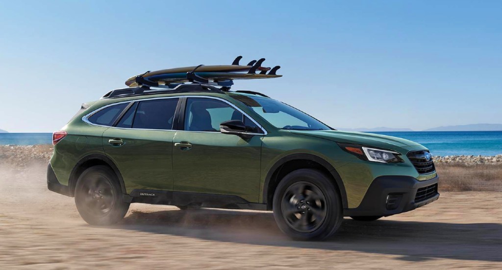 A green Subaru Outback SUV is off-roading in the sand. 