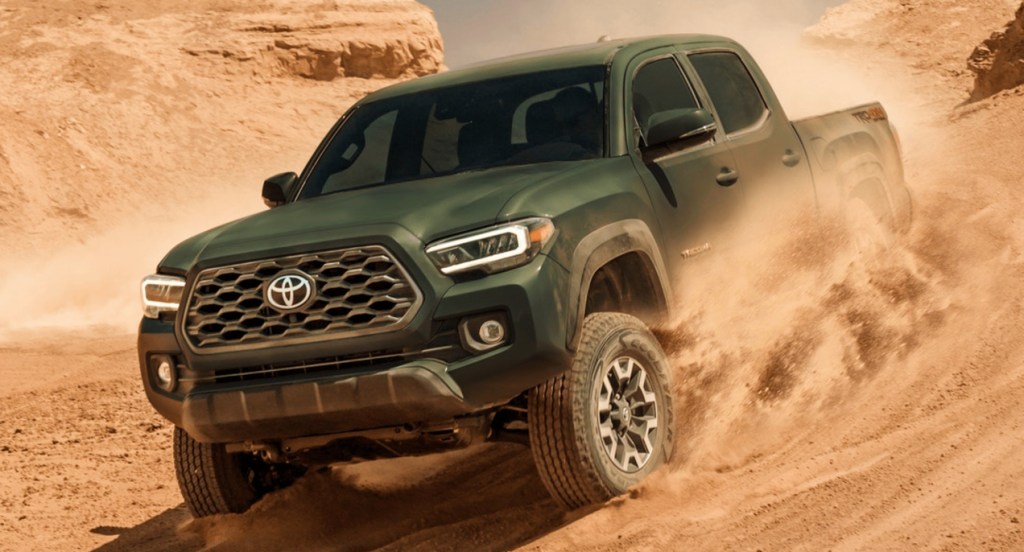 A green Toyota Tacoma is off-roading. 