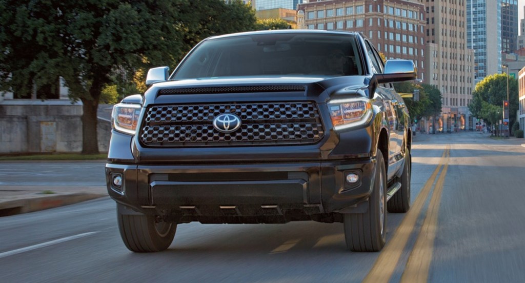 A black Toyota Tundra is driving down the street in a city. 