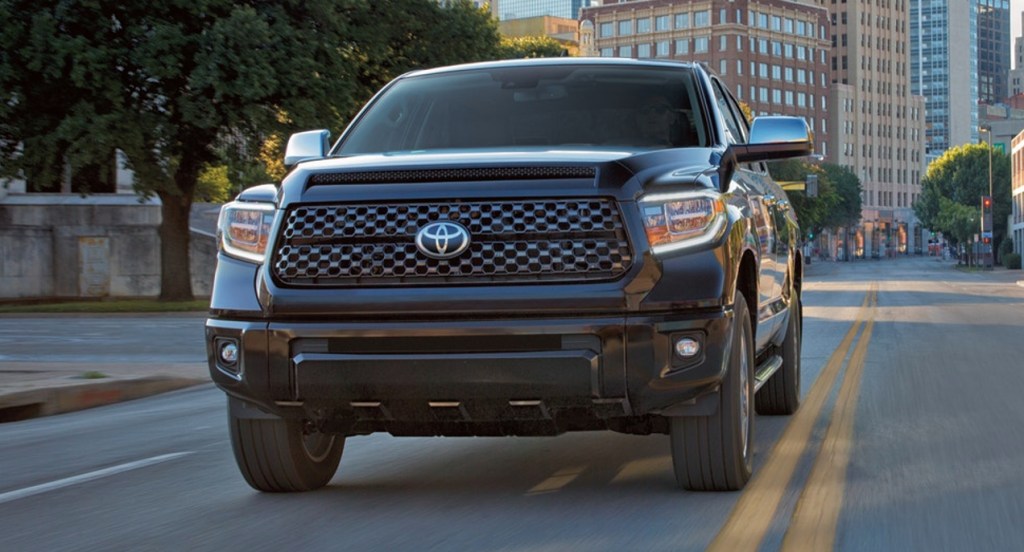 A black Toyota Tundra pickup truck is driving in a city.