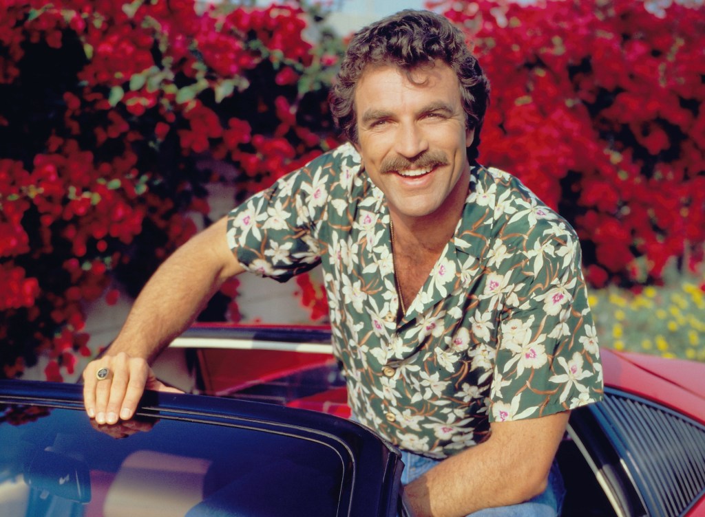 Tom Selleck sits in a red Ferrari 308 for the CBS TV series 'Magnum, P.I.' in January 1984