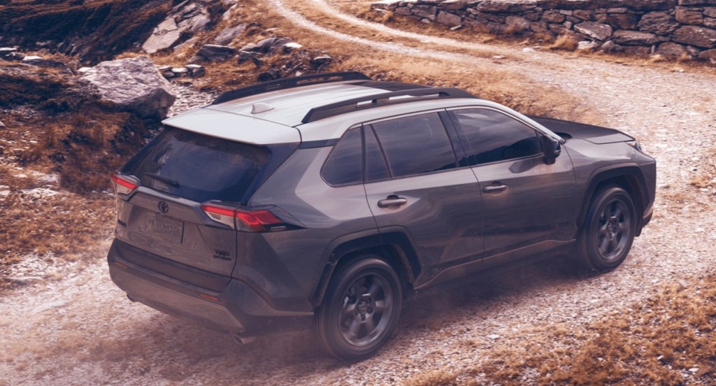 A gray 2021 Toyota Rav4 TRD Off-Road. is on a trail. Rocks and a winding trail leading to a steep hill are in the background. 