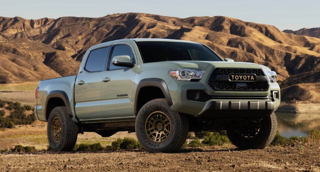 A green Toyota Tacoma pickup truck is parked on dirt. 