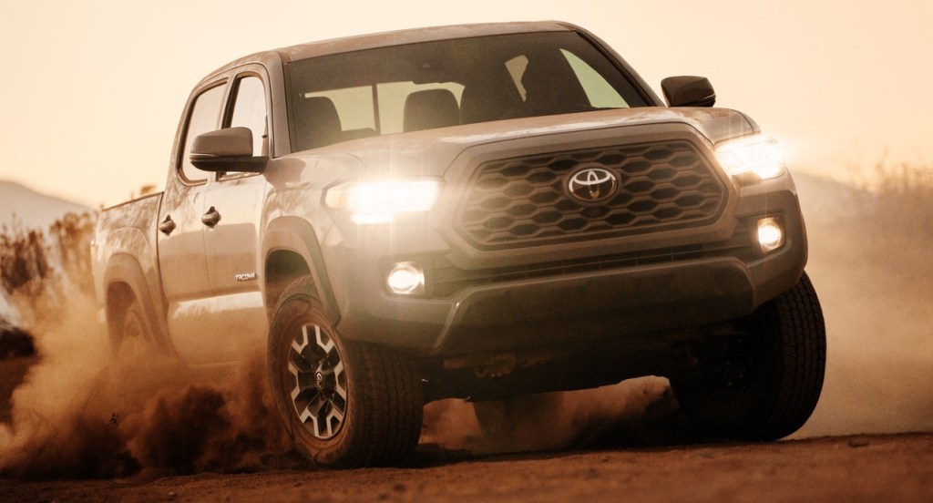 A gray Toyota Tacoma pickup truck is kicking up dust off-roading. 