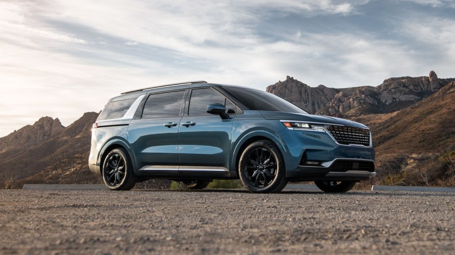 Turquoise 2022 Kia Carnival with mountains in the background