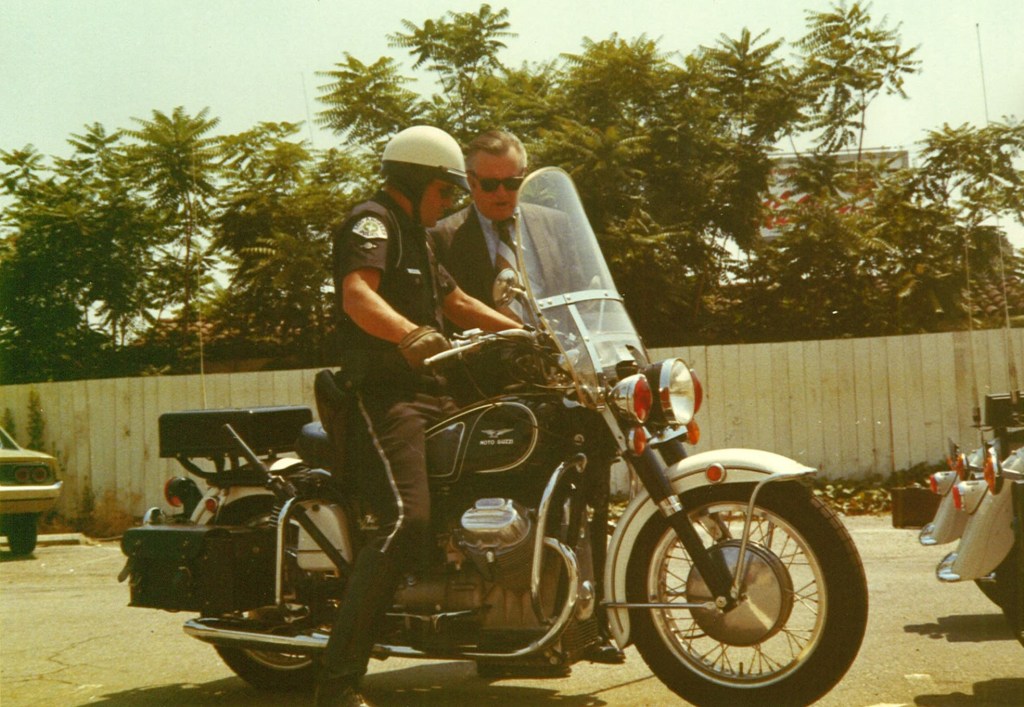 Two Los Angeles police officers look over a Moto Guzzi Eldorado 850 police bike in a 1970s parking lot