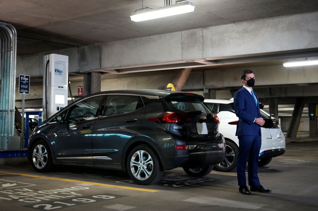 US Secretary of Transportation Pete Buttigieg by an EVgo public EV charging station in a parking garage