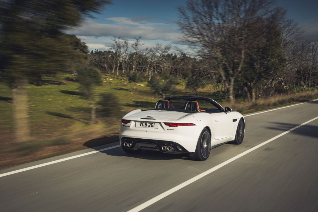 White 2022 Jaguar F-TYPE driving by a forest