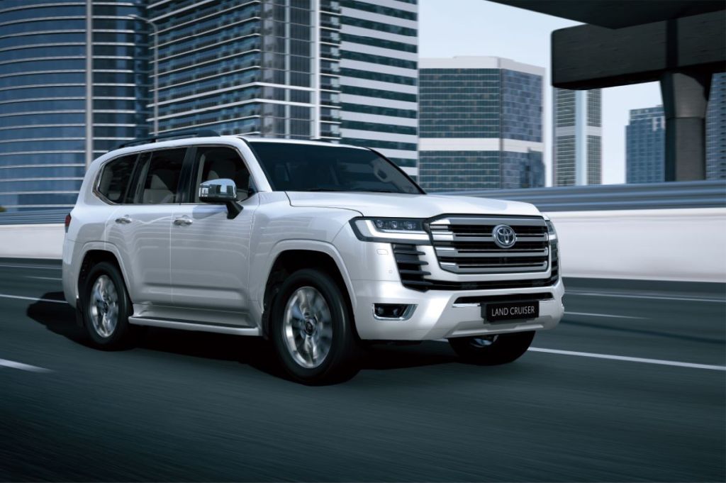 A white 2021 Toyota Land Cruiser driving by tall buildings