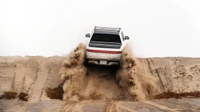 White Rivian R1T driving up a sand dune