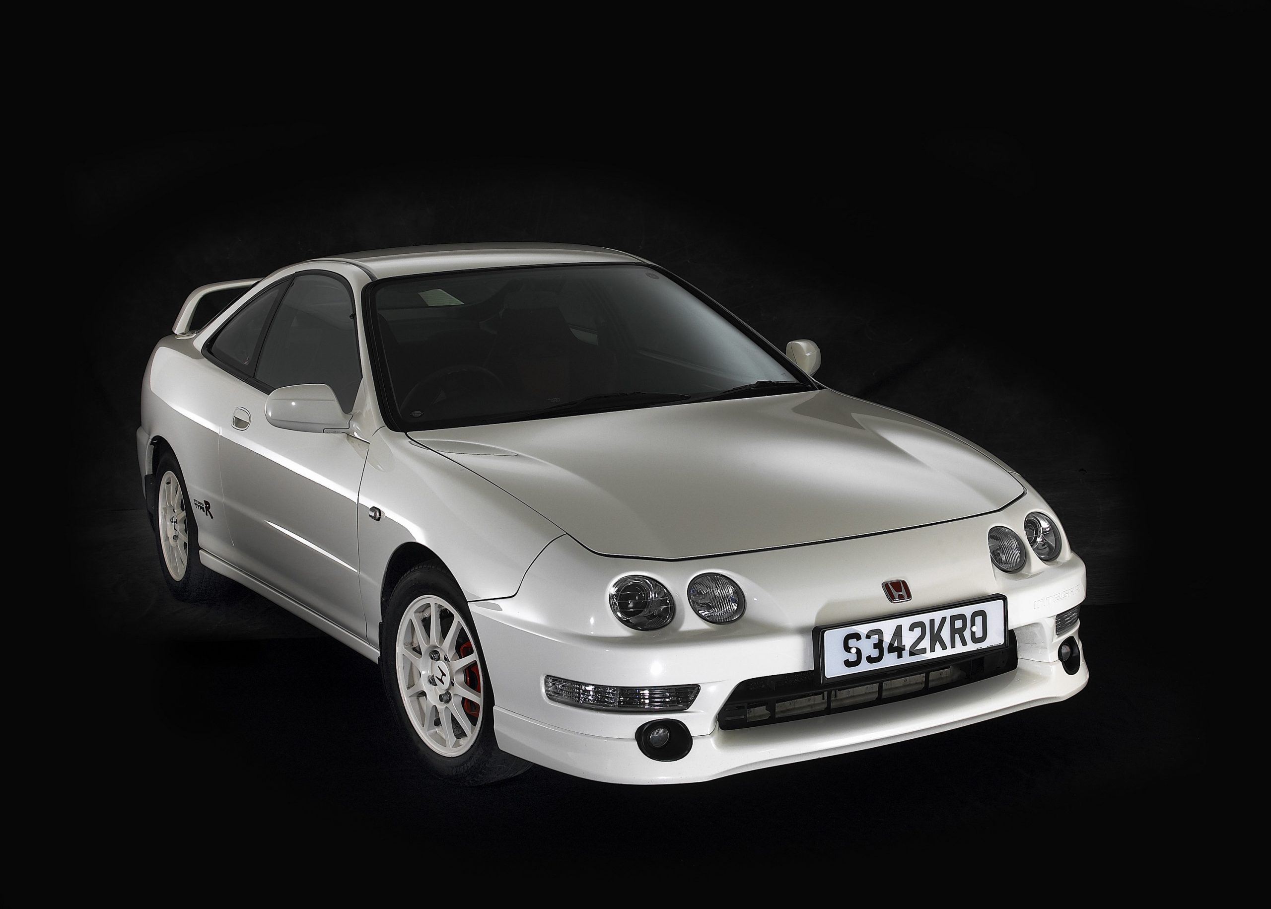 A white Acura Integra Type R shot from the front 3/4 in a black studio