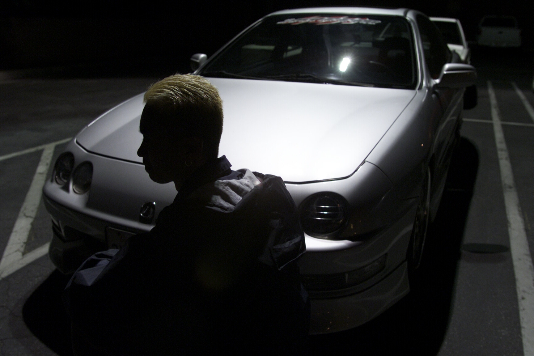 A '90s white Acura Integra and its driver shot from the front 3/4