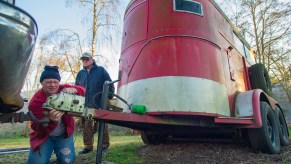 A man hitches a horse trailer to a ball hitch for towing