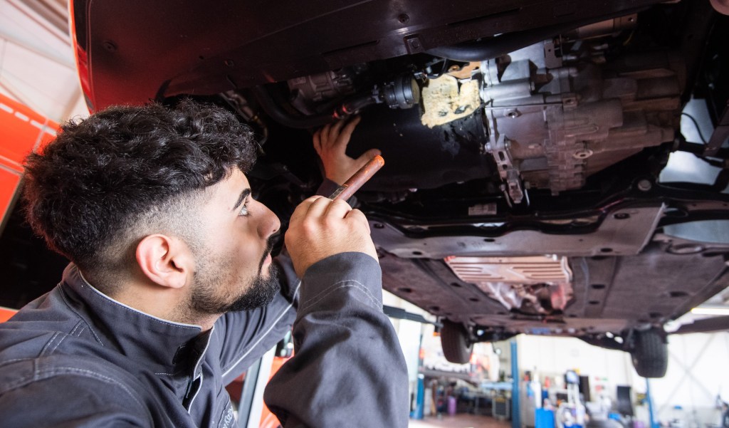 An apprentice automotive mechatronics technician inspects damage to a VW Touran in a Volkswagen workshop in the Hanover region.