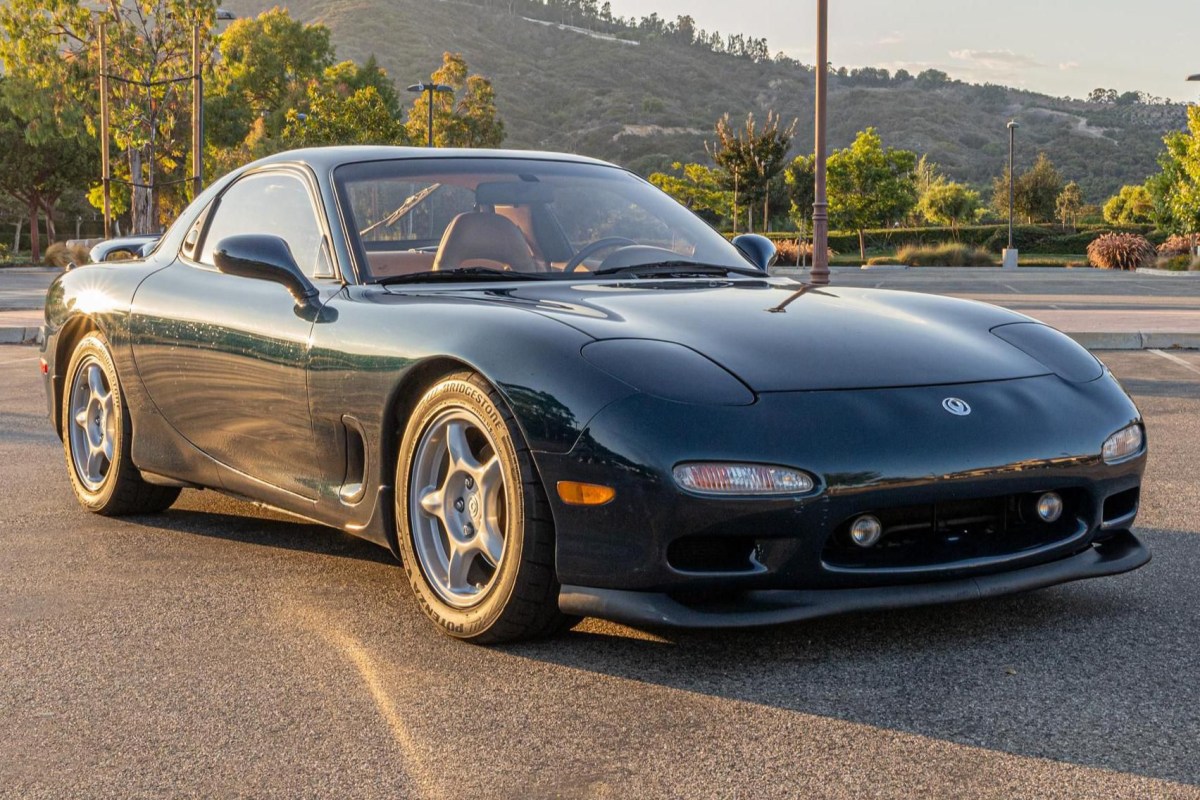 Forrest Green 1993 Mazda RX-7 in a parking lot with the sun setting behind it.