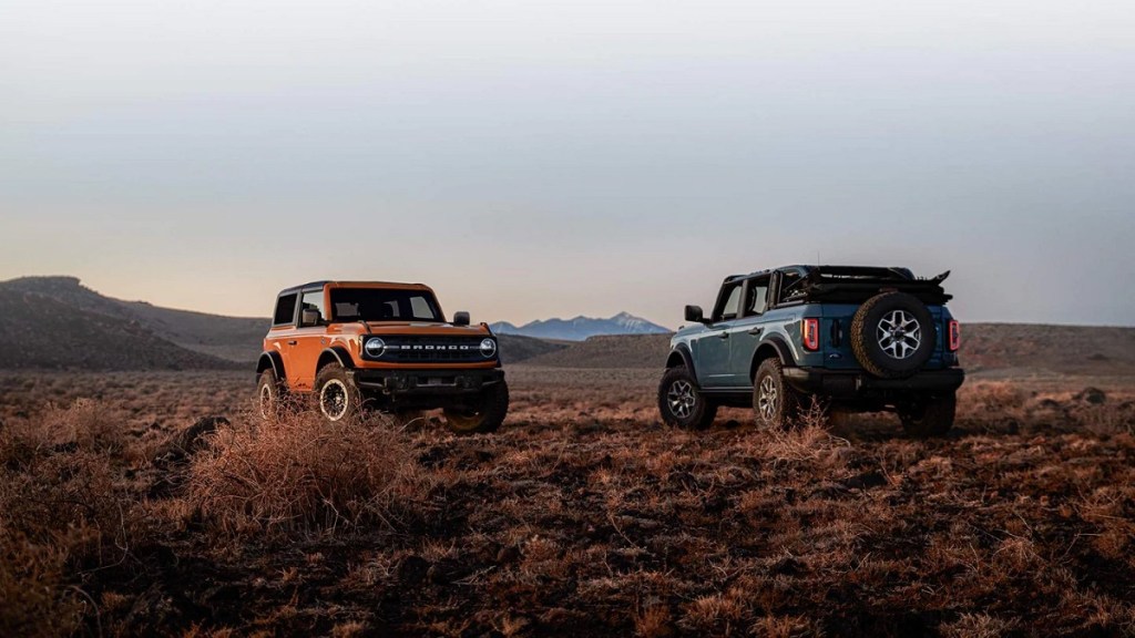 An orange and a blue 2021 Ford Bronco facing each other in the mountains.