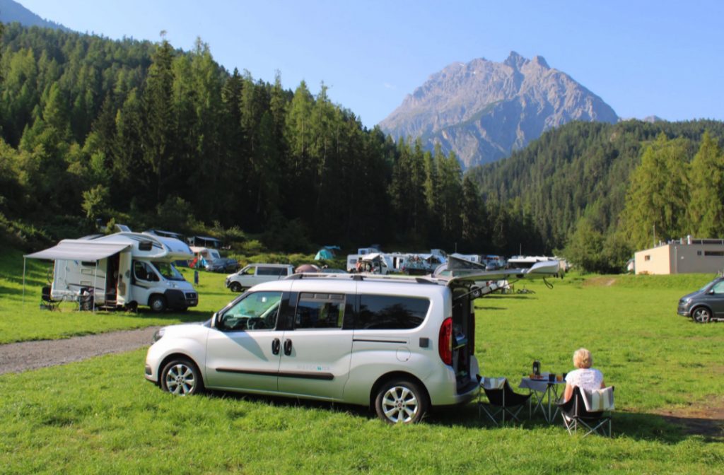 The Dailycamper seen in a field in front of a mountain range. This also happens to be one of the most affordable camper vans on the maket, as well as, a great small camper van 