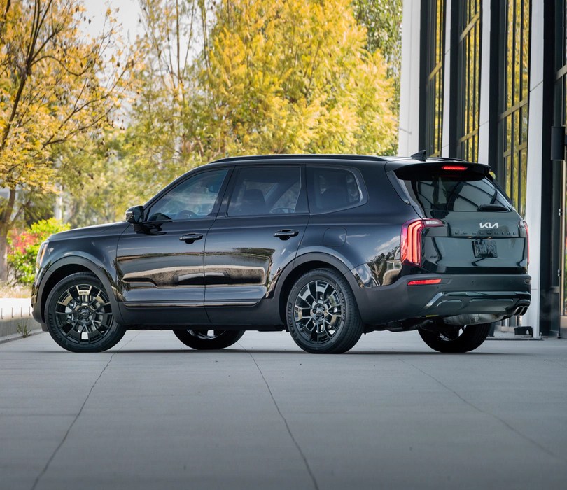 A dark-colored 2021 Kia Telluride sits outside of a house.