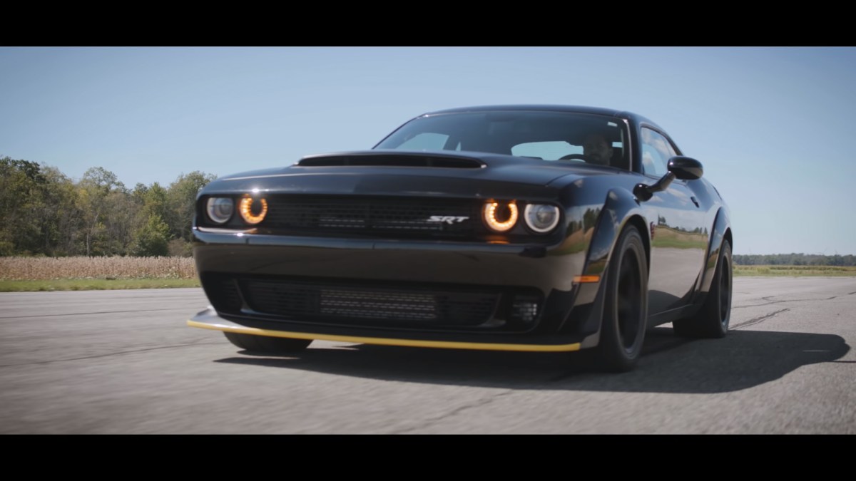 A black Dodge Demon with a yellow front lip spoiler preparing for a drag race