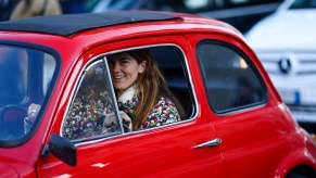 A smiling woman driving a red car in Italy in January 2020