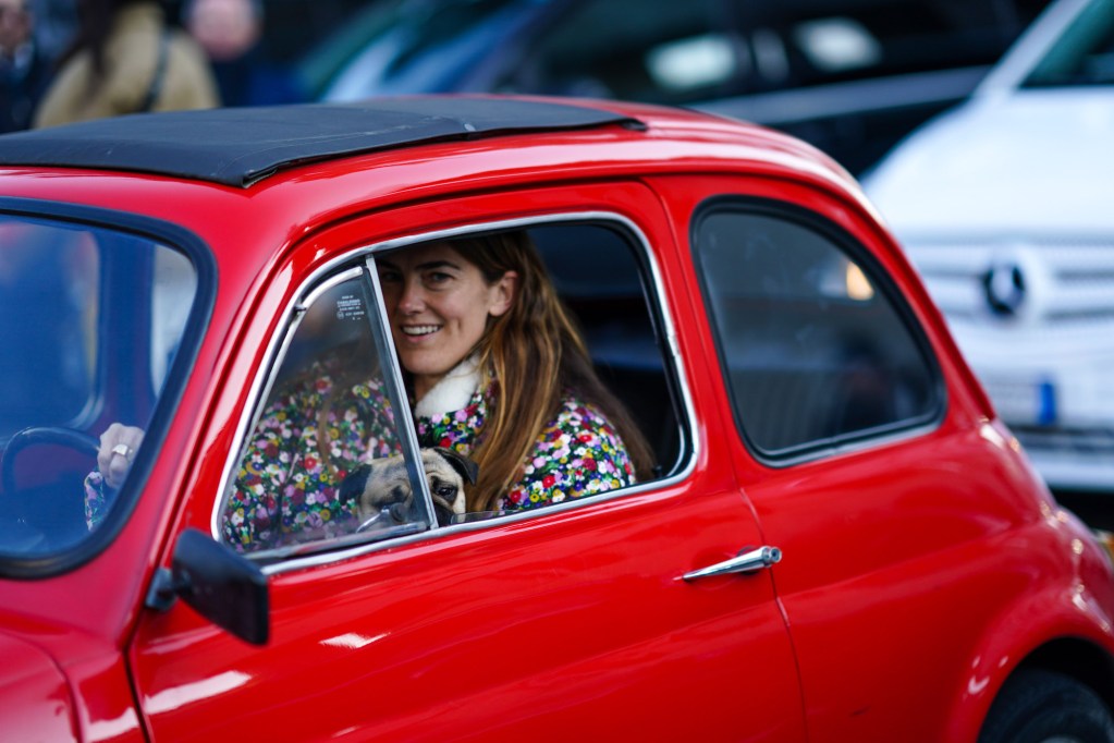 A smiling woman driving a red car in Italy in January 2020
