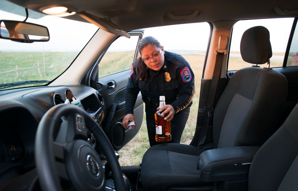 A man is arrested for drunk driving while police Sgt. Dawn White removes an open bottle of whiskey from his car in North Dakota