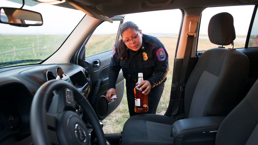 A man is arrested for drunk driving while police Sgt. Dawn White removes an open bottle of whiskey from his car in North Dakota