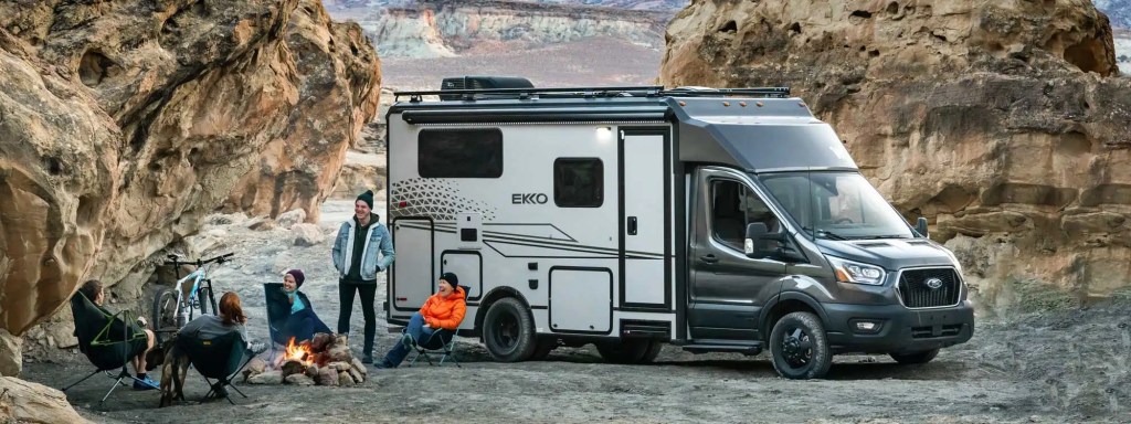 The Winnebago Ekko rules the small RV world. This photo shows people gathered a fire pit with the ekko in the background. 
