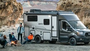The Winnebago Ekko rules the small RV world. This photo shows people gathered a fire pit with the ekko in the background.