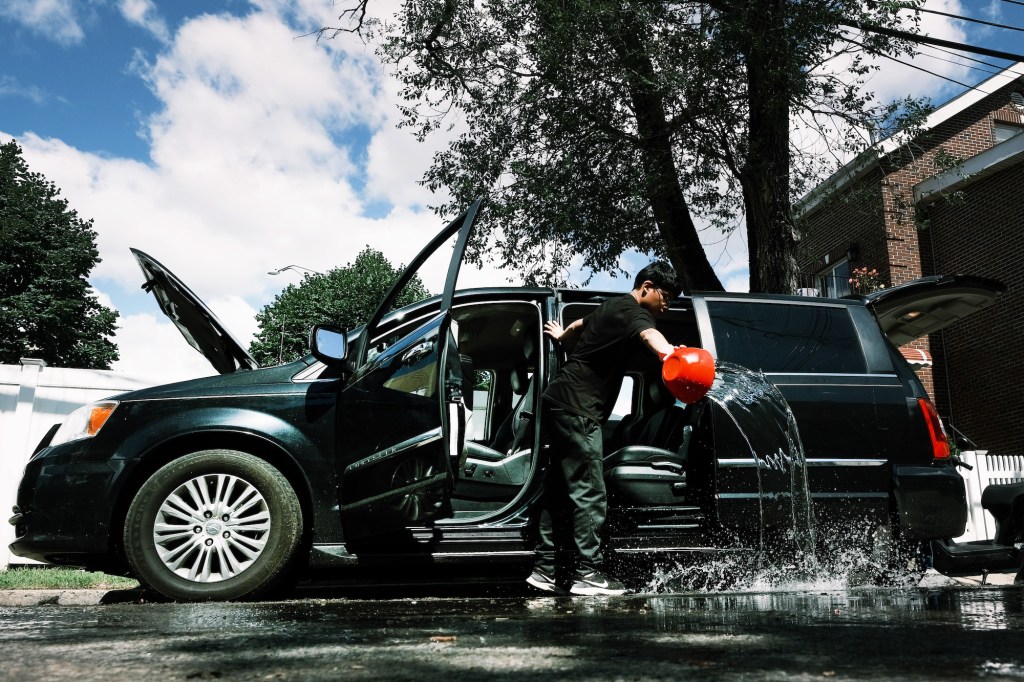 A teen cleans a flooded-damaged car in New York City after Hurricane Ida