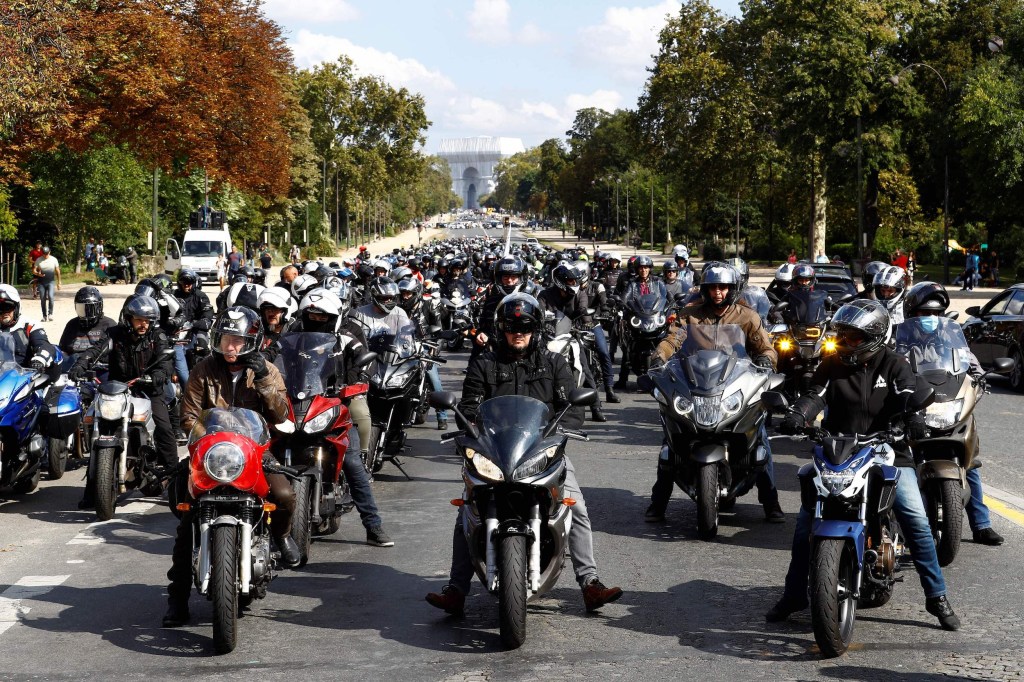 Motorcyclists gather, as the Arc de Triomphe, wrapped in silver-blue fabric as it was designed by late artist Christo, is seen in the background, during a demonstration against a parking reform for Paris which will impose paying parking for non-electric motorcycles and scooters, on September 18, 2021, in Paris. 