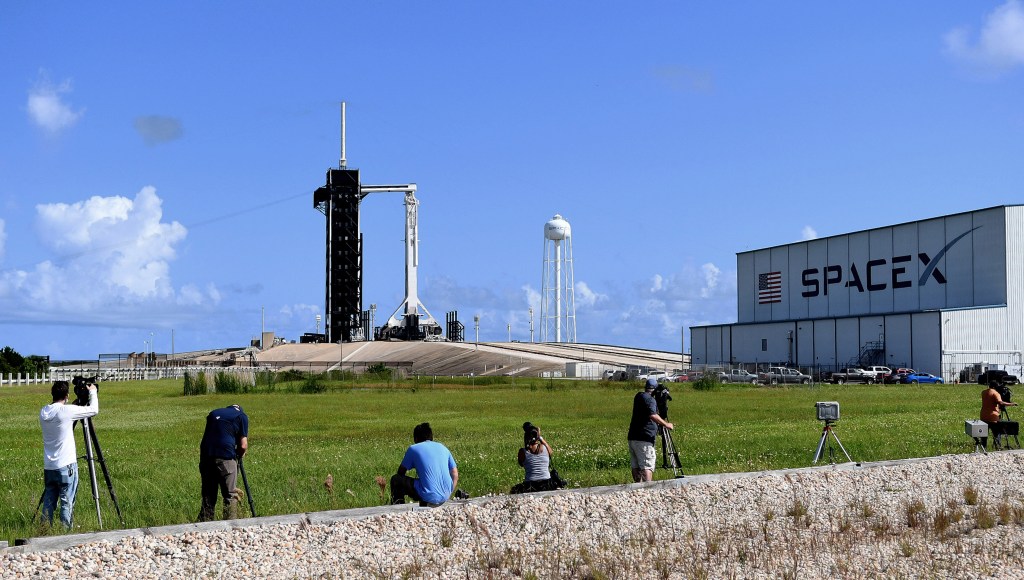 Media photographers set up cameras to take the launch of the Falcon 9 rocket and a Crew Dragon capsule