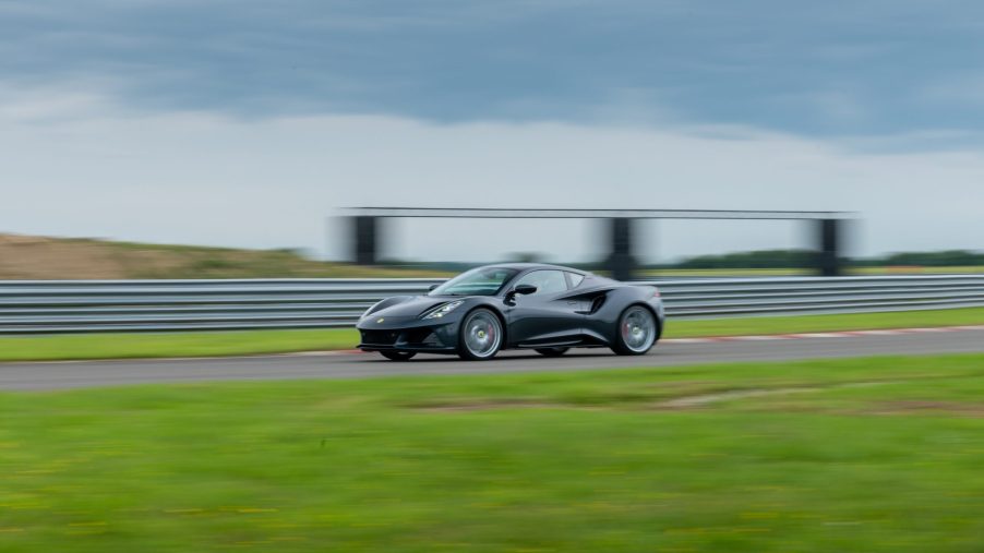 A black Lotus Emira on a racetrack, shot from afar in profile