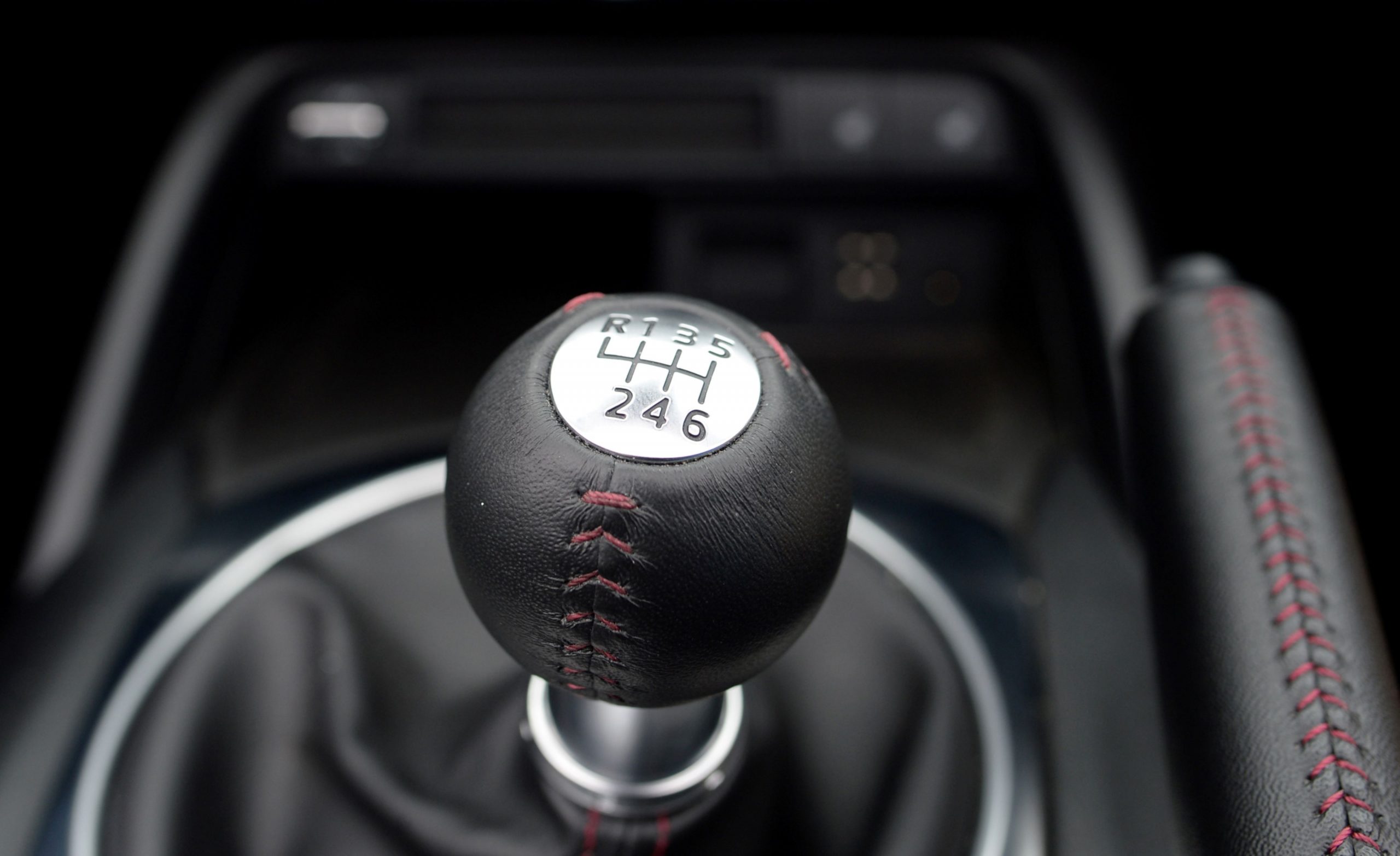 Manual transmission shift knob inside of a vehicle with black interior.
