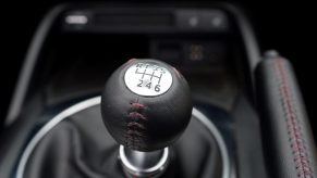 Manual transmission shift knob inside of a vehicle with black interior.