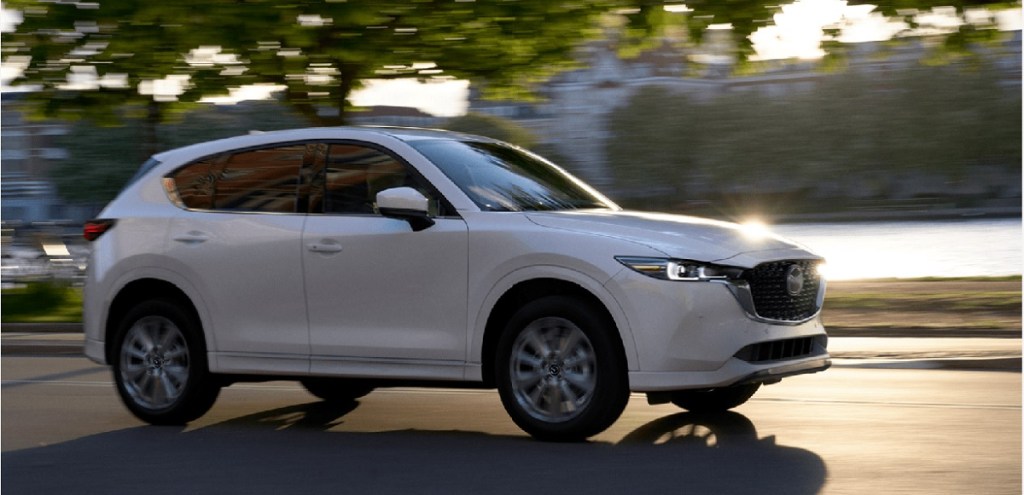 A white 2022 Mazda CX-5 driving by water.