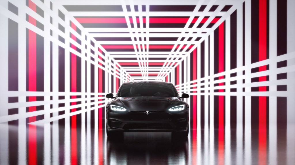 A black Tesla Model S Plaid in a plaid-patterned photo booth