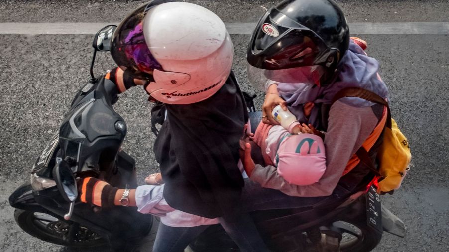 A motorcycle passenger feeds a baby a bottle of milk in Jakarta on August 9, 2017