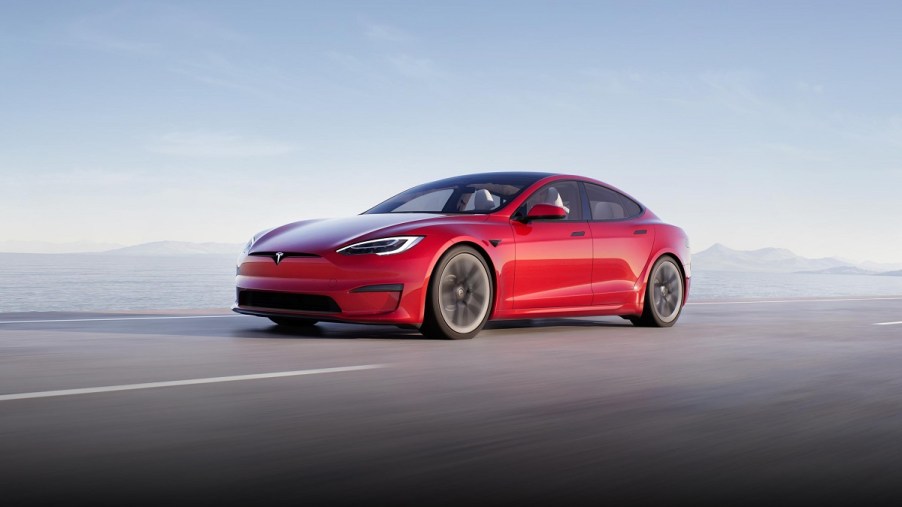 A red 2021 Tesla Model S driving down a road. These cars will now have Tesla Safety Score to determine if a driver should have the Full Self Driving mode