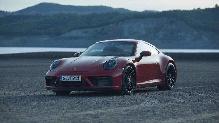 A red Porsche 911 GTS on a beach at sunset, shot from the front 3/4