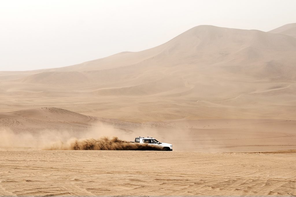 The 2022 Rivian R1T rips through the desert, kicking rooster tails high behind it